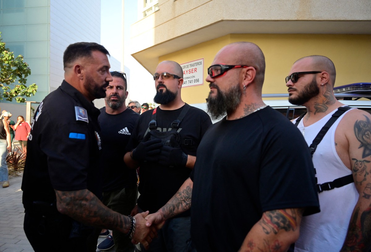 A Police officer (L) greets members of Desokupa in Spain.