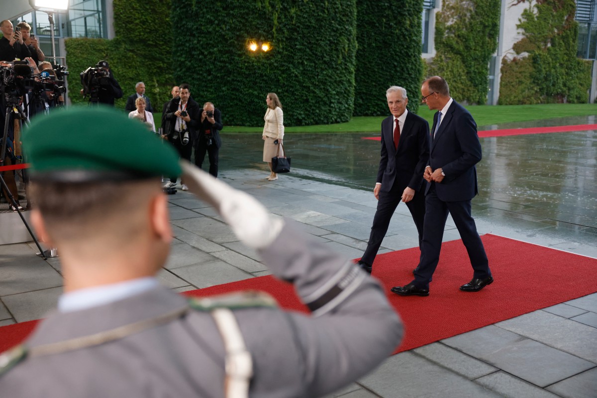 Norwegien Prime Minister and Merz walk through the rain in Berlin.