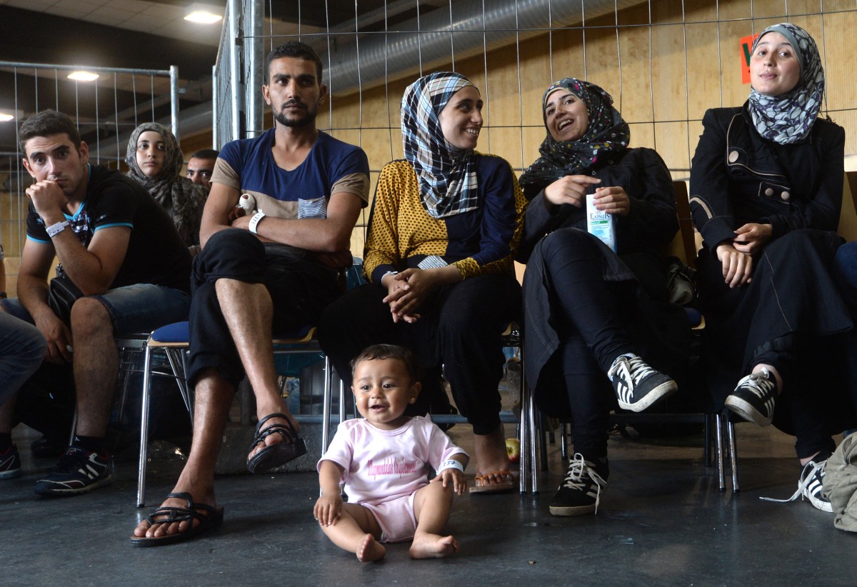 A group of Syrians are seen siting together with a baby.