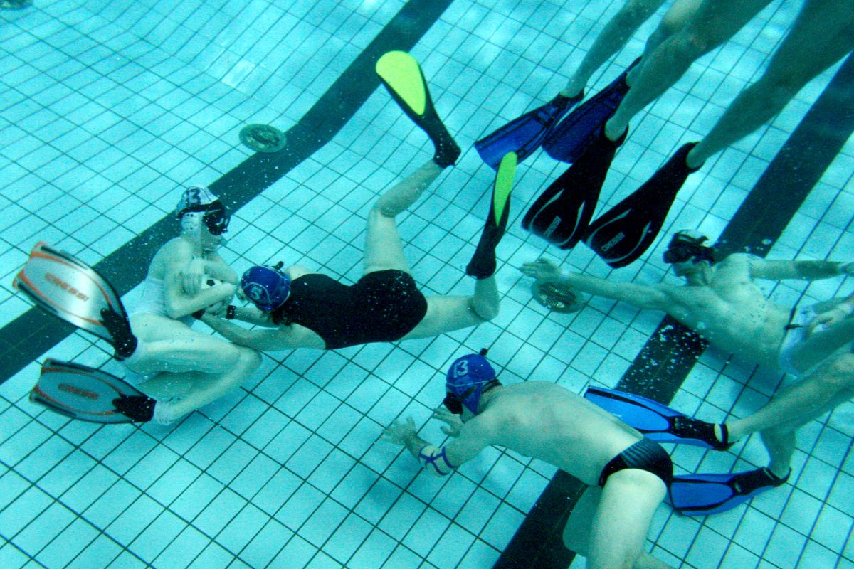 men and women play underwater rugby in a swimming pool