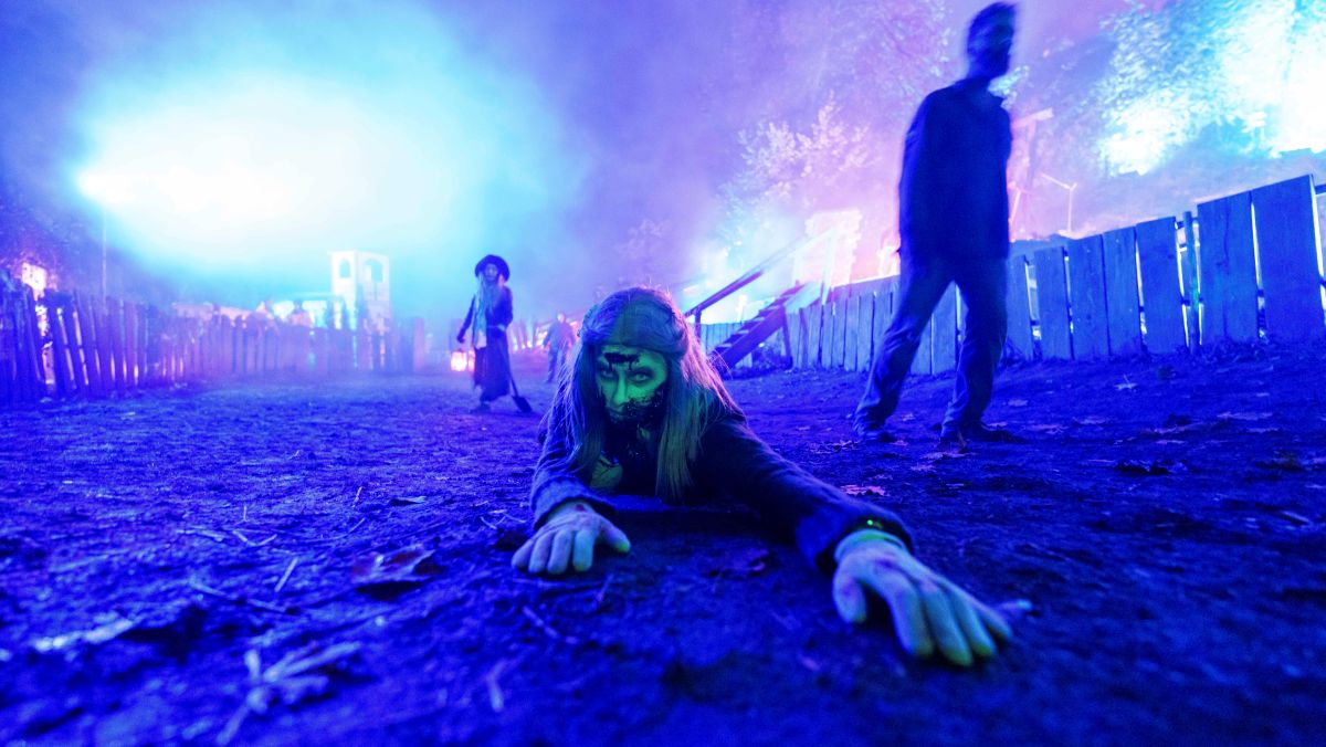 A zombie with a green face crawls toward the camera.