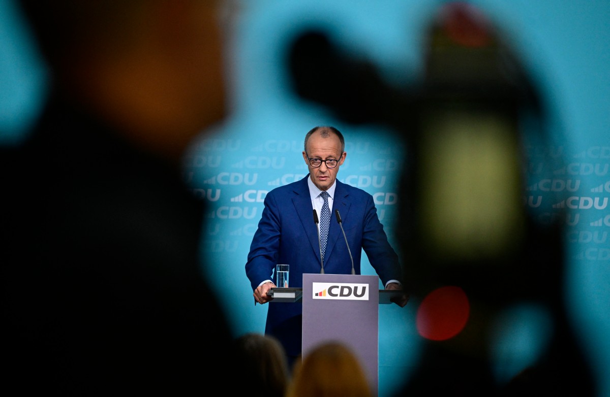 Merz makes a speech at a podium.