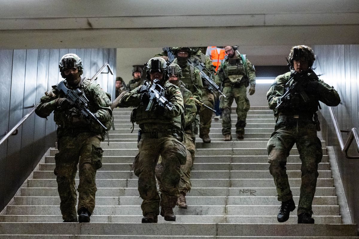 Soldiers come running down a stairwell in an U-bahn station.