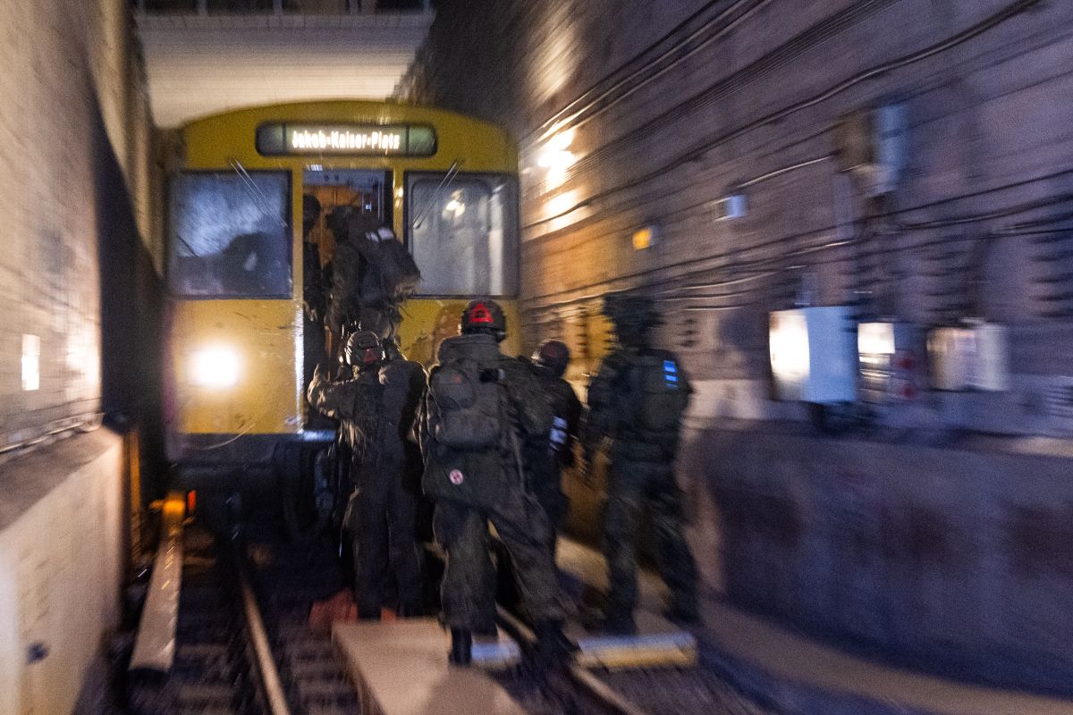 Soldiers enter a train from its rear door in an underground tunnel.