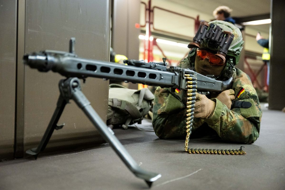 A soldier lays on the ground with an automatic gun.
