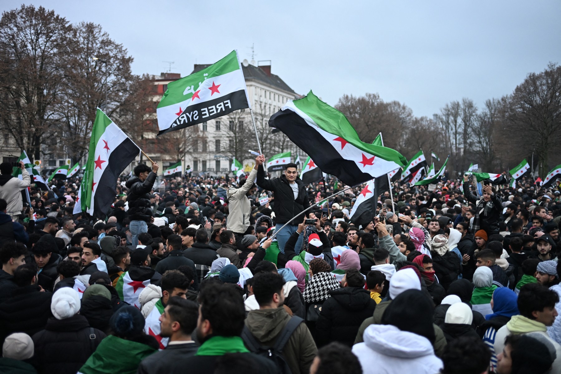 Members of the Syrian community wave Syrian flags at a rally on December 8, 2024 in Berlin to celebrate the end of Syrian dictator Bashar al-Assad's rule.