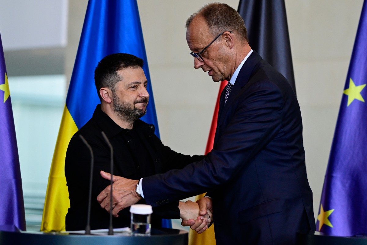 Ukrainian President Volodymyr Zelensky and German Chancellor Friedrich Merz shake hands after addressing a joint press conference after a video conference of European leaders with the US President on the Ukraine war ahead of a summit between the US and Russian leaders, in Berlin, on August 13, 2025.