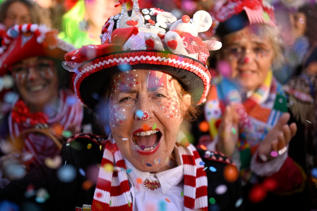 A woman in elaborate clown makeup yells in excitement in the Carnival crowd in Cologne.