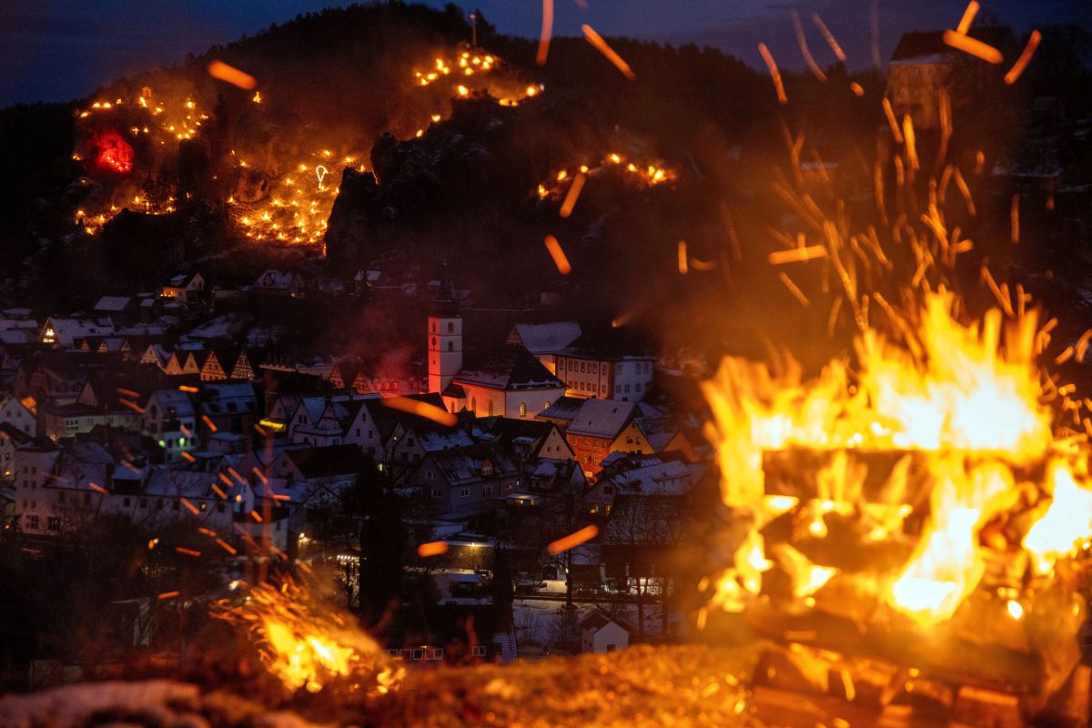 A fire burns in the foreground with dozens seen in the hillside over Pottenstein.