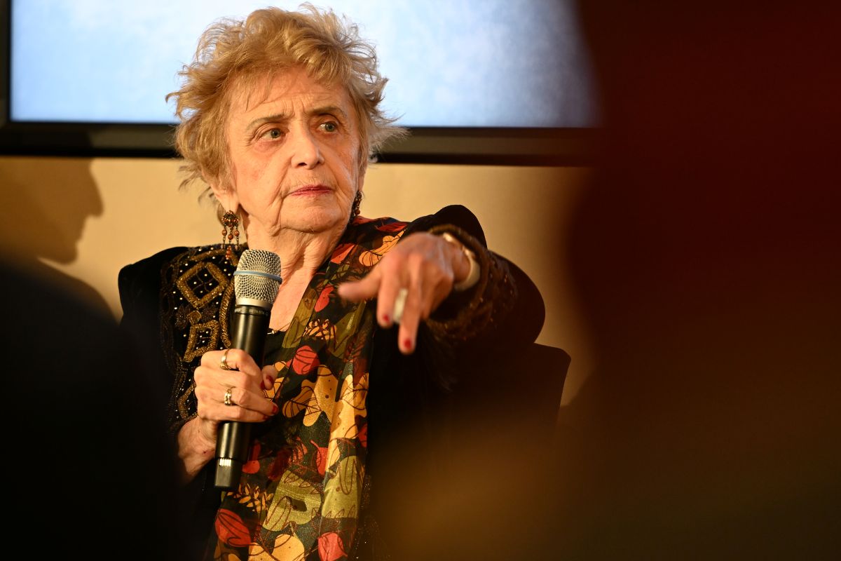 Tova Friedman, holocaust survivor, looks serious with a microphone in her hand.