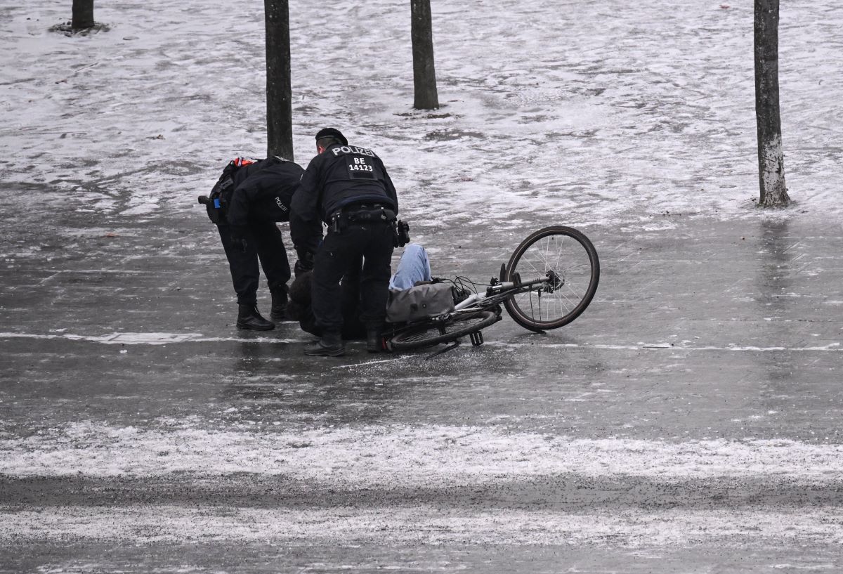 Police officers help a cyclist who has slipped on black ice.