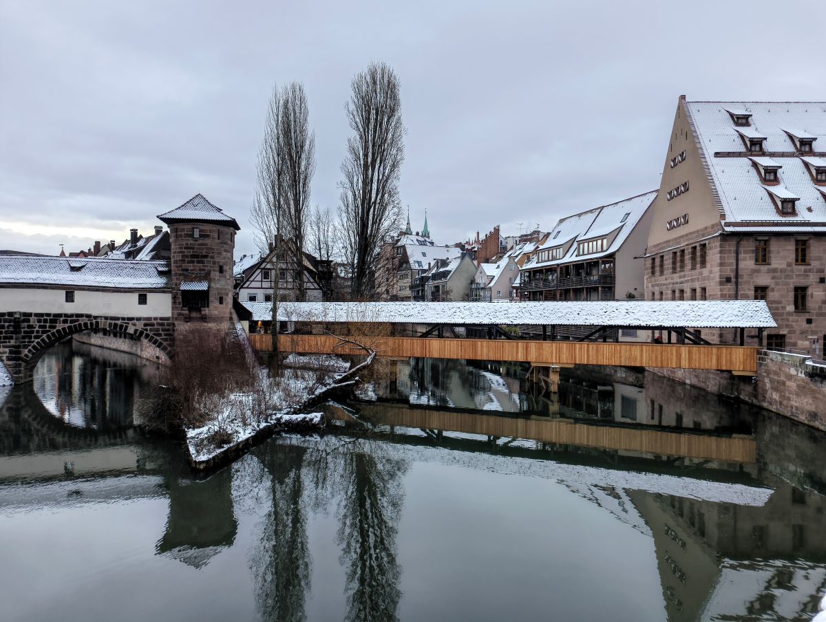 A view of Nuremberg's old town, where a covered bridge and several old buildings are covered in a think layer of snow.