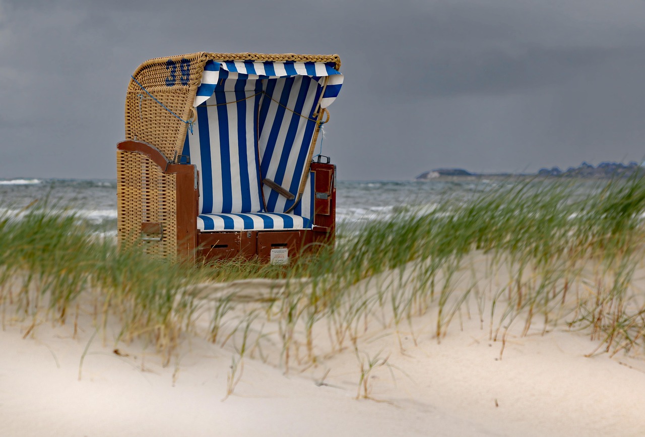 A Strandkorb chair is seen on the beach on a gloomy day.