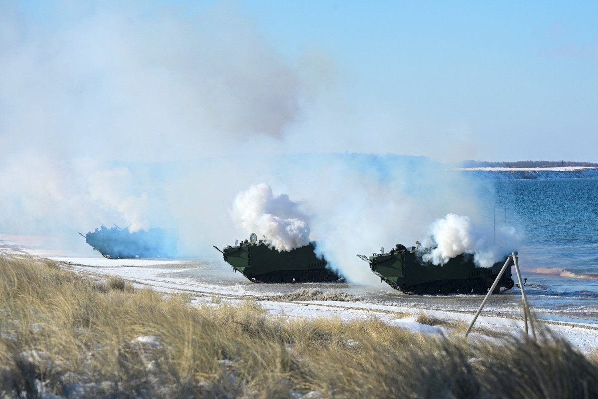 Three aquatic military vessels pull onto the beach in plumes of smoke.
