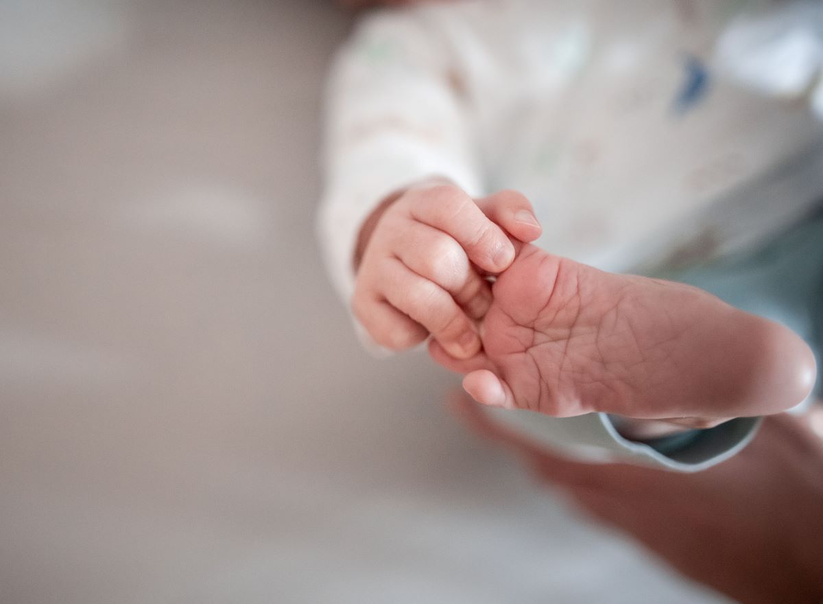 A baby reaches for its foot with its fingers.