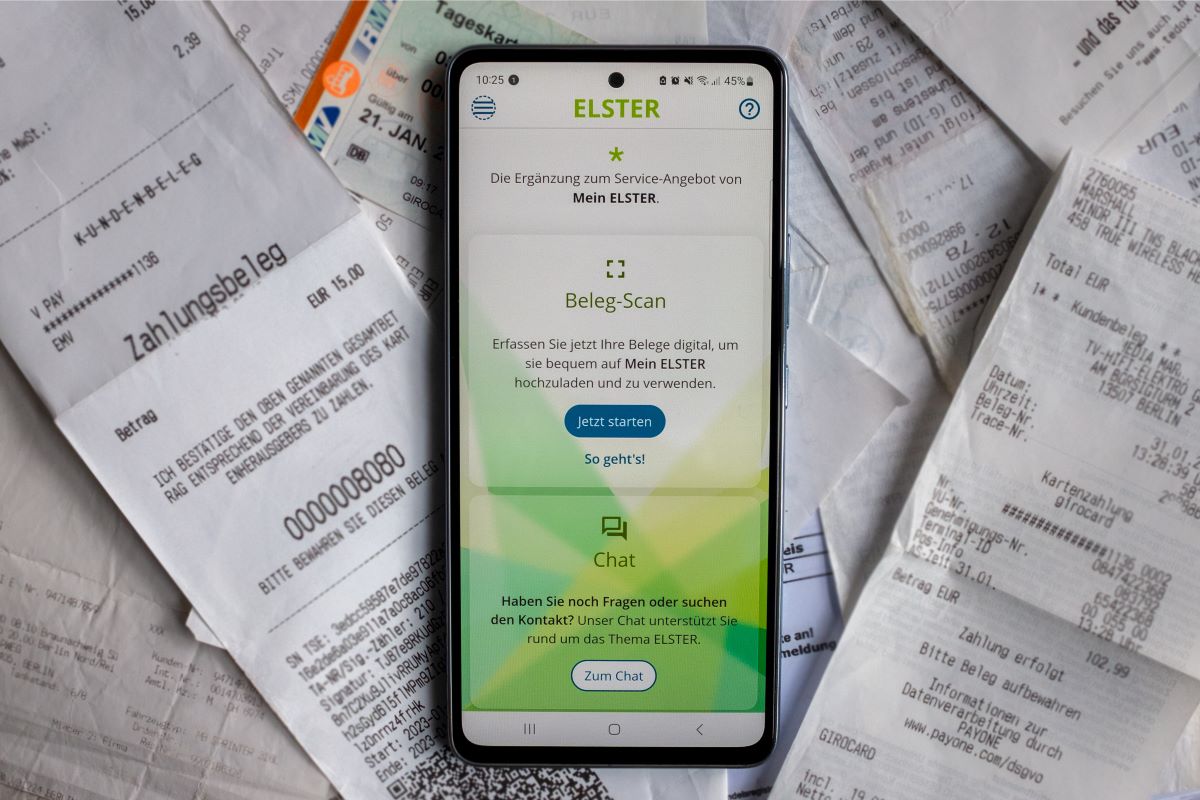 A smart phone showing a tax app sits on a pile of receipts