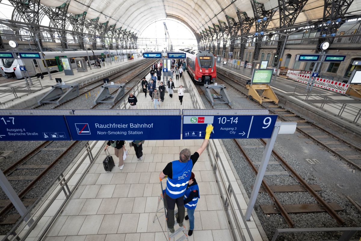 Two people are cleaning a platform in the main concourse of Dresden Central Station as part of a press event.