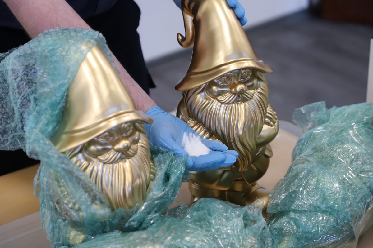 Two golden gnomes are seen along woth a bag full of white powder.