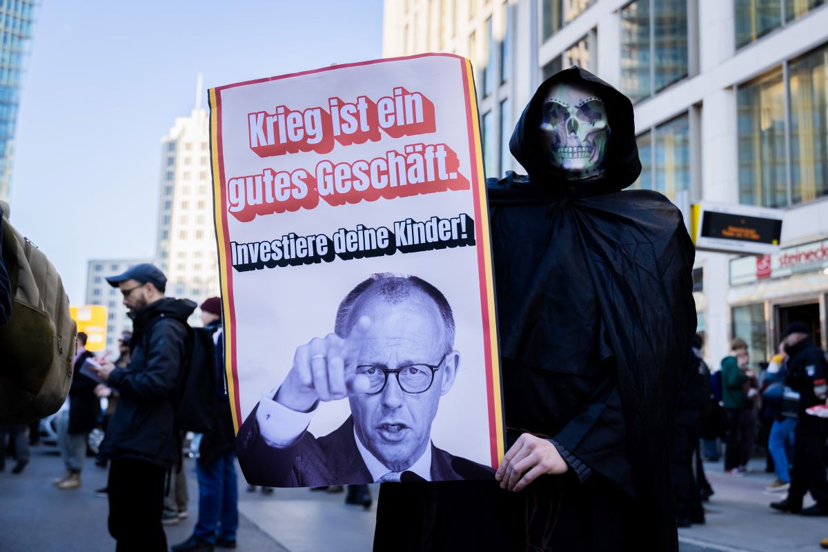 A participant wearing a skull mask holds a sign reading “War is good business. Invest your children!” at a demonstration during the nationwide school strike against compulsory military service. 