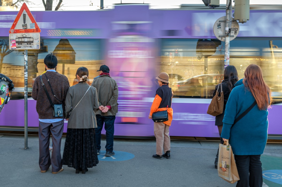 Pedestrians stand on a sidewalk as a city tram passes by on a Ring boulevard in Vienna, Austria on a sunny day on March 5, 2026.