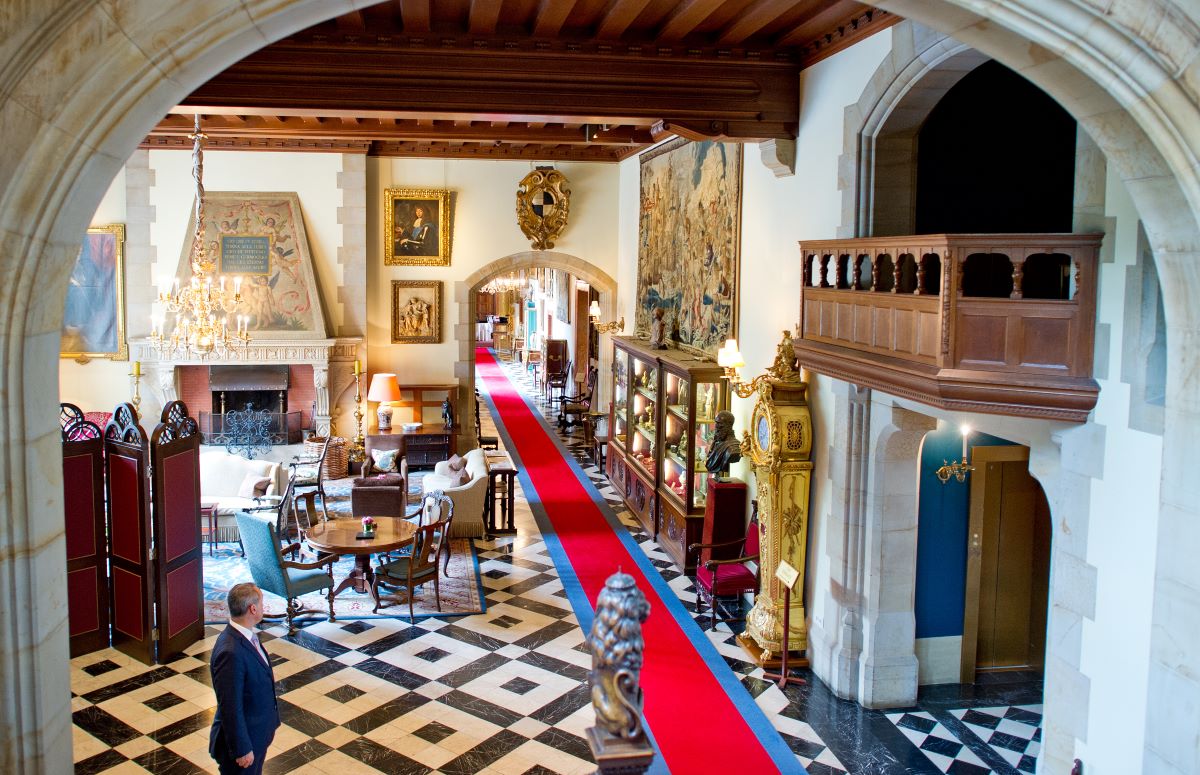 A hotel hobby with red carpet, marble floor and wooden balcony