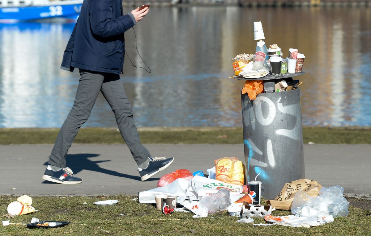 A trash can and party trash lying next to it in Treptower Park.