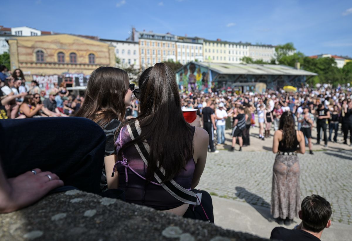 People are seen sitting on the stone blocks in Gorlitzer park in Berlin in front of a large crowd.