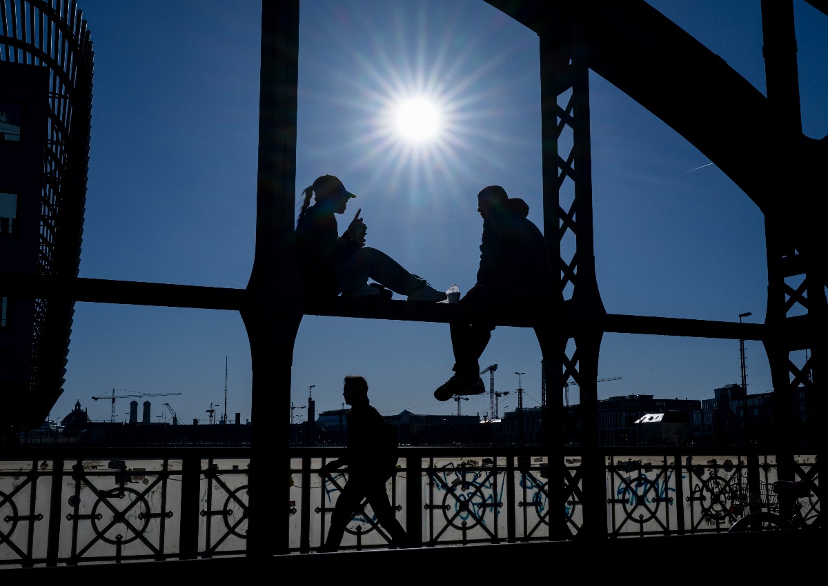 People enjoy the morning sunshine on the Hackerbrücke in Munich.