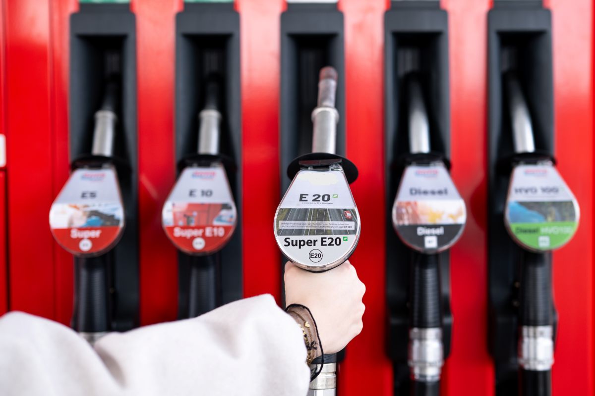A hand reaches for a petrol pump.