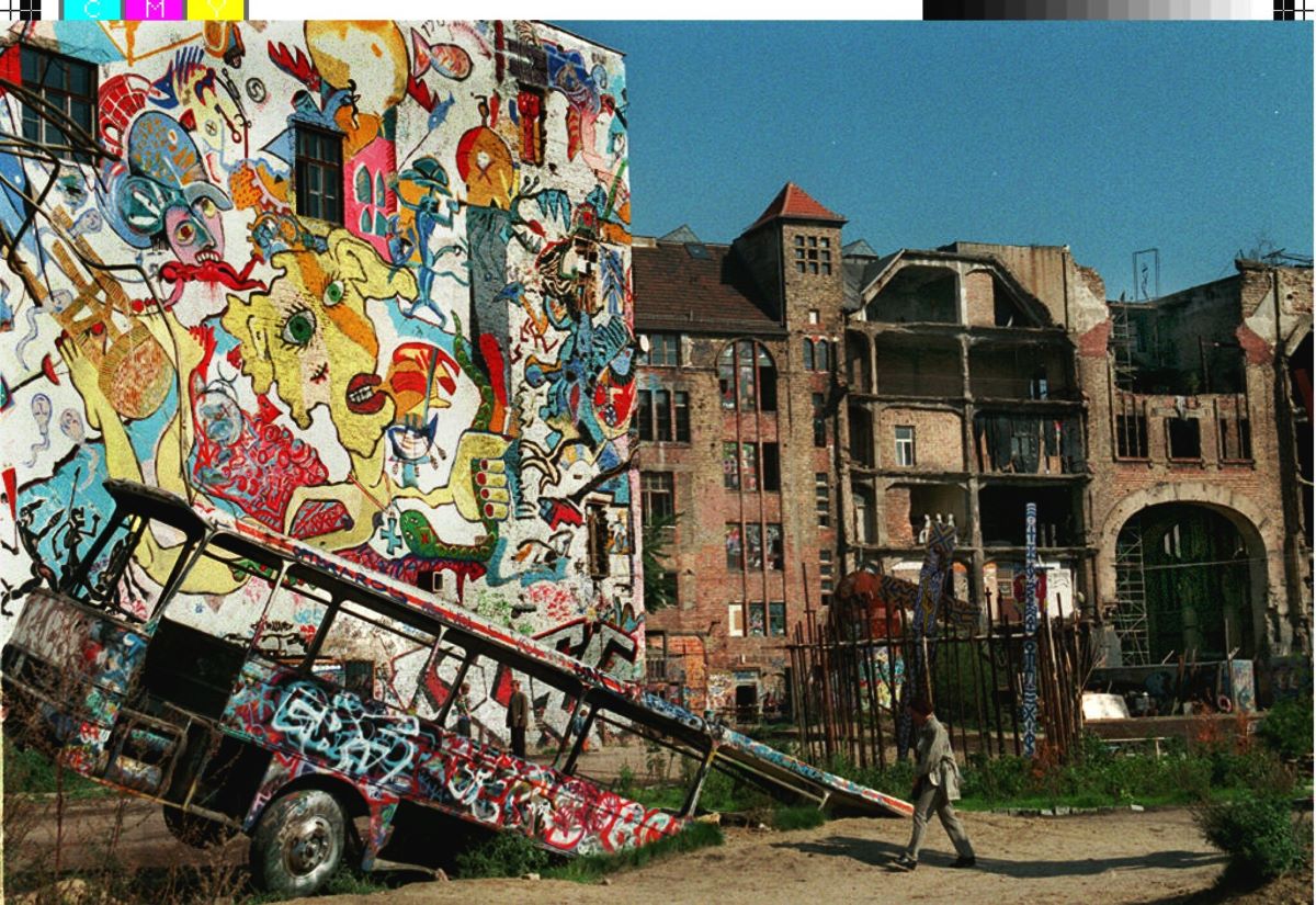 A partially buried former tour bus stands in front of a massive, graffiti-covered building wall at the Tacheles cultural workshop in Berlin’s Mitte district.