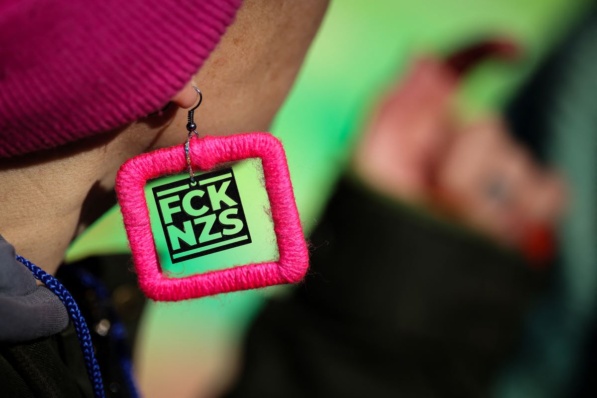 A protester wears an ear ring reading "FCK NZS" as she takes part in a demonstration outside the Hyparschale hall in Magdeburg,