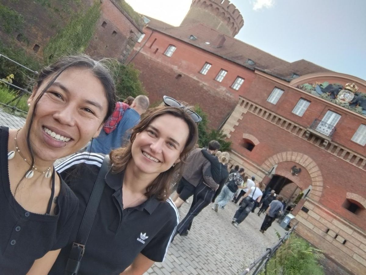 Emilia and Darya smile at the camera standing in front of a red brick castle.