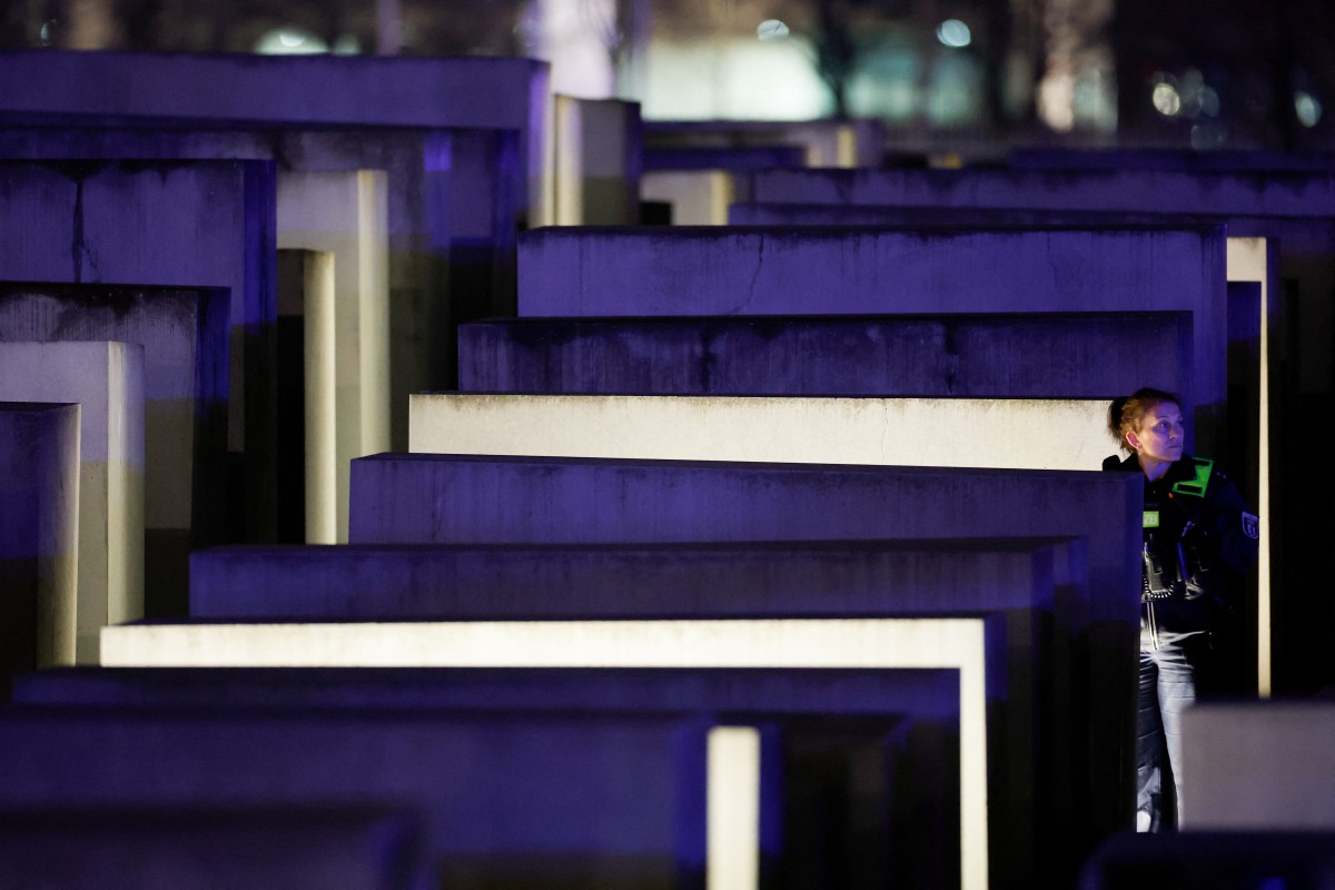 A police officer is seen anoung the concrete slabs of the Holocaust memorial at night.