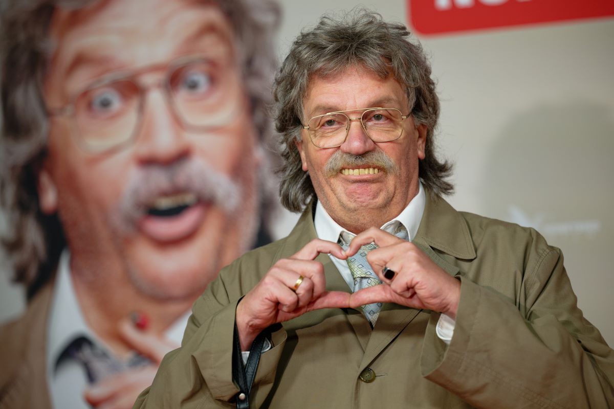 A man with bad teeth makes a heart shape with his fingers