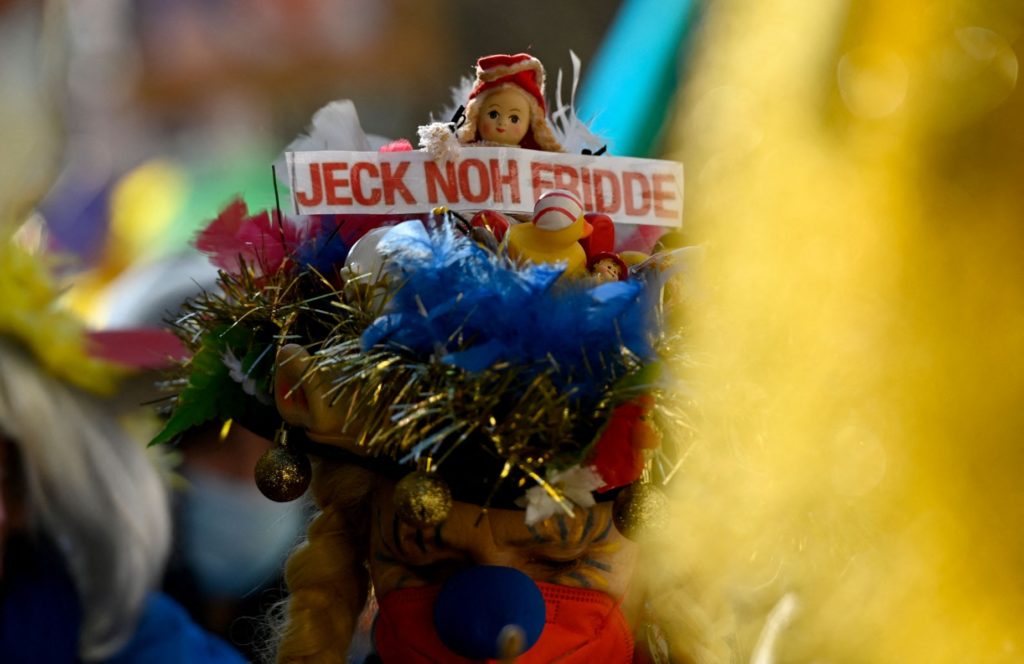 A reveller wears a fancy headdress with a lettering written in Cologne's dialect and reading "Crazy for Peace" during a peace march titled "Freedom for Ukraine" replacing the traditional Rose Monday carnival street parade in Cologne, western Germany, on February 28, 2022.