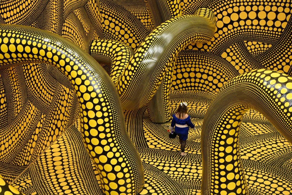 A woman walks through the installation "Infinity Mirrored Room The Hope of the Polka Dots Buried in Infinity Will Eternally Cover the Universe" during a preview for an exhibition of the work of Japanese artist Yayoi Kusama at the Museum Ludwig in Cologne