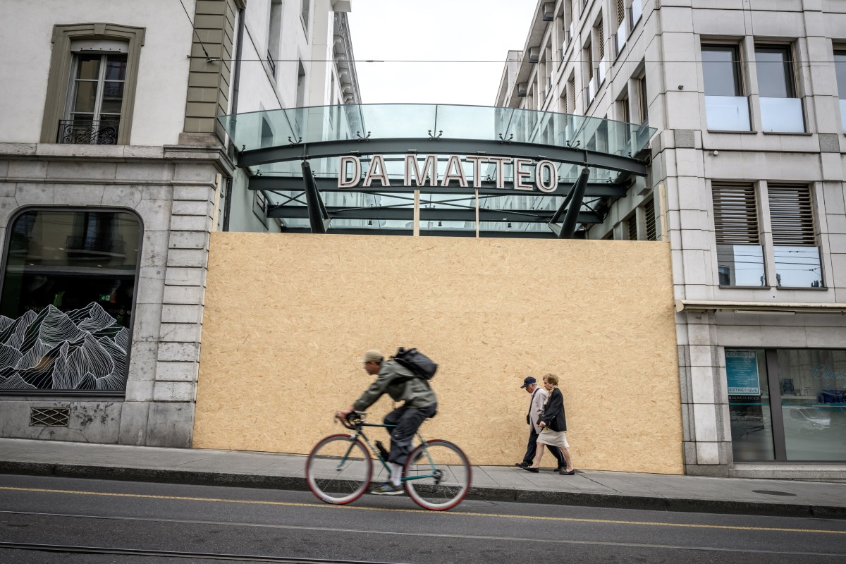 Passer-by walks past the entrance of a restaurant boarded up
