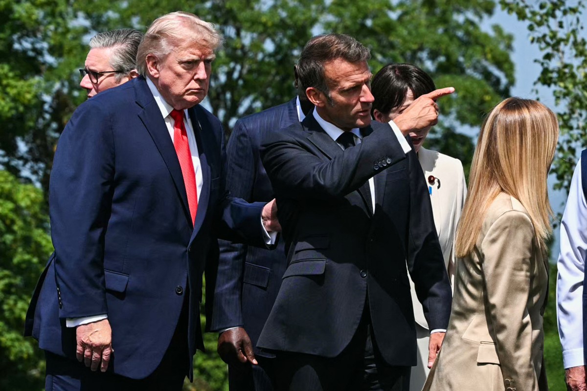 US President Donald Trump (L) listens to France's President Emmanuel Macron (C)