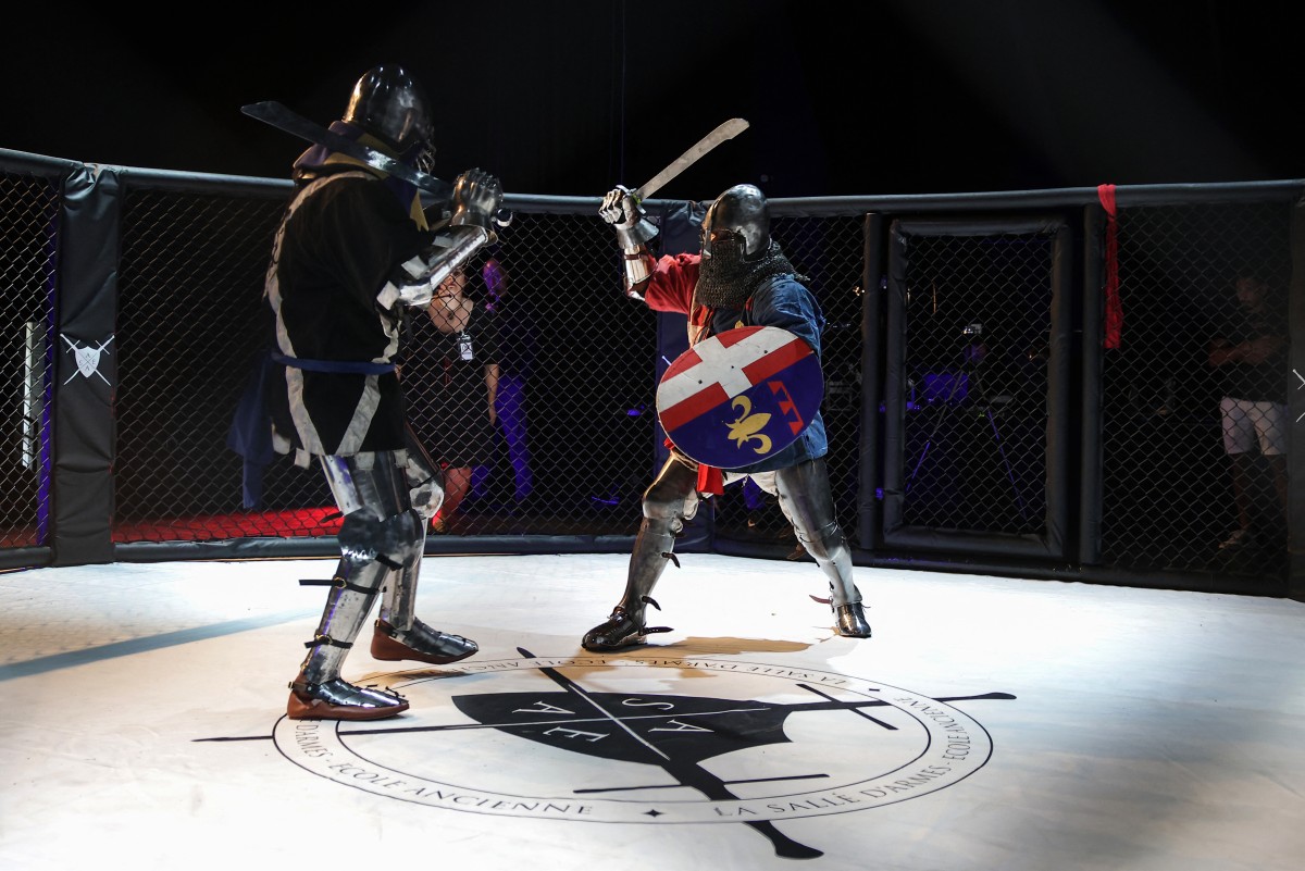 Competitors fight with swords in an MMA (mixed martial arts) arena