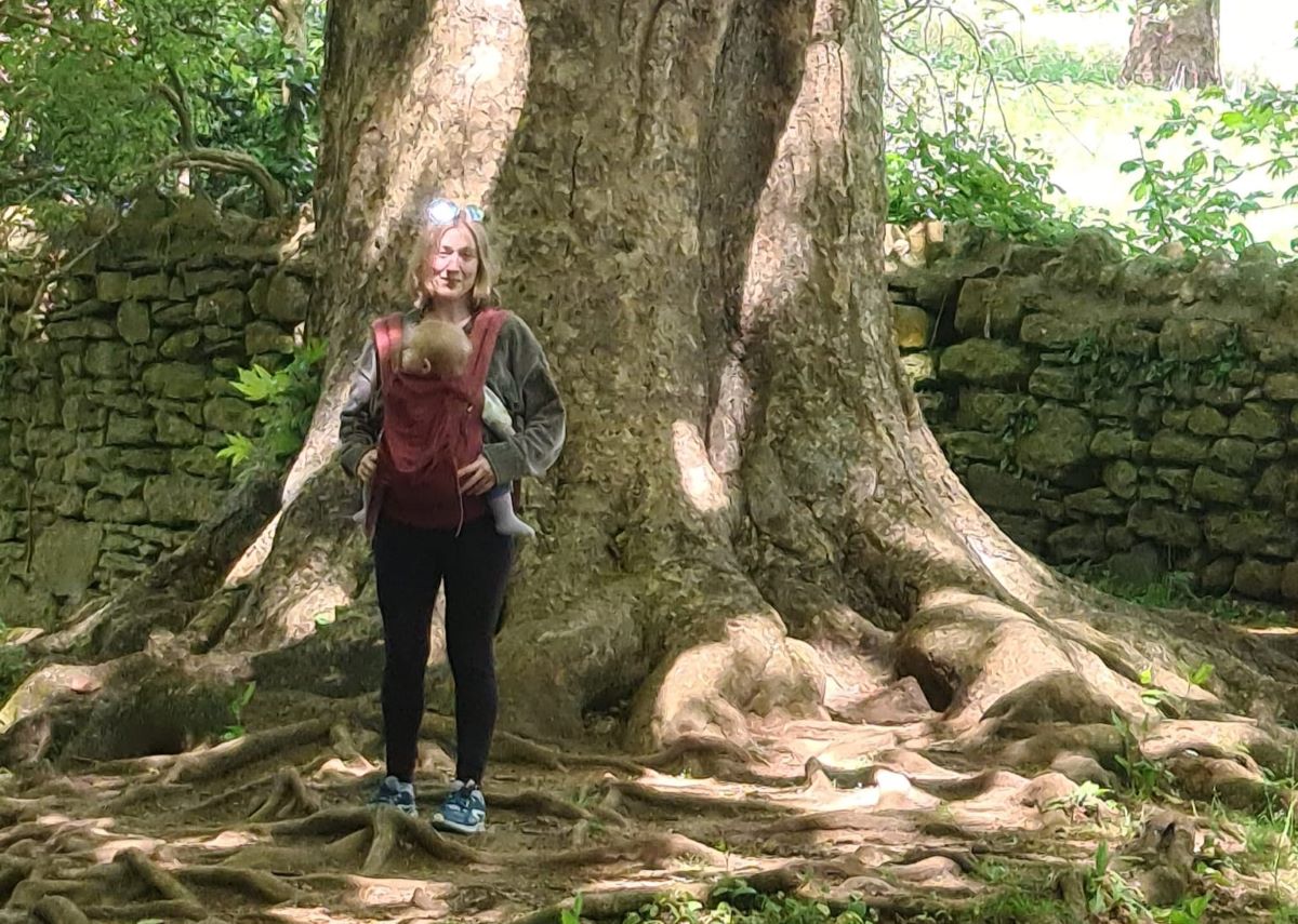 a mother and her child stand in front of a tree
