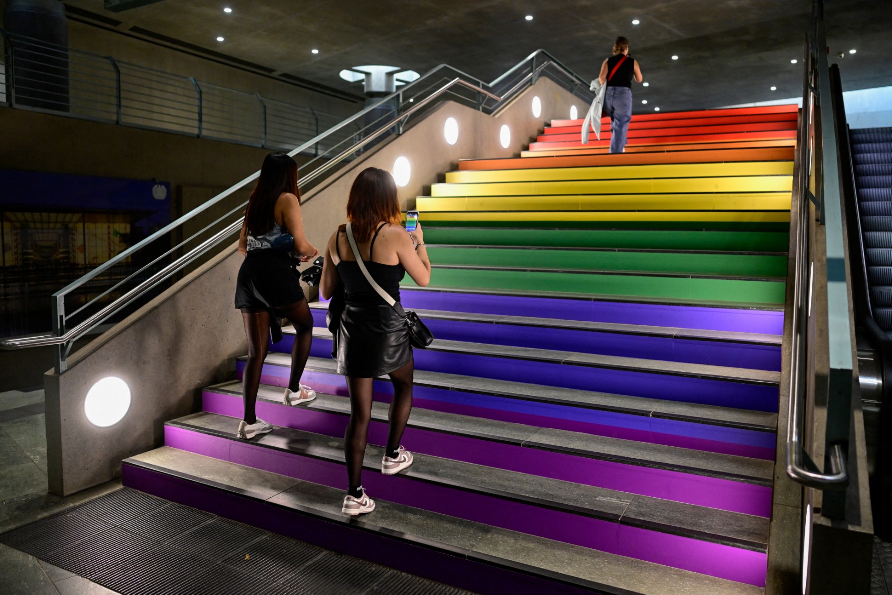 Commuters walk up the steps of the Bundestag subway station, decorated with the rainbow flag colours, the symbol of the LGBTQ+ community