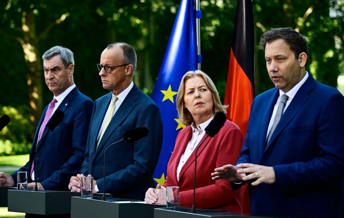 Germany's federal leaders are seen in suits lined up at a podium presenting their tax reforms.
