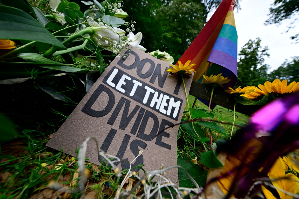 Flowers and a sign with the lettering 'Don't let them divide us' placed in tribute to the victims at the Tiergarten park in Berlin on July 27, 2026. 