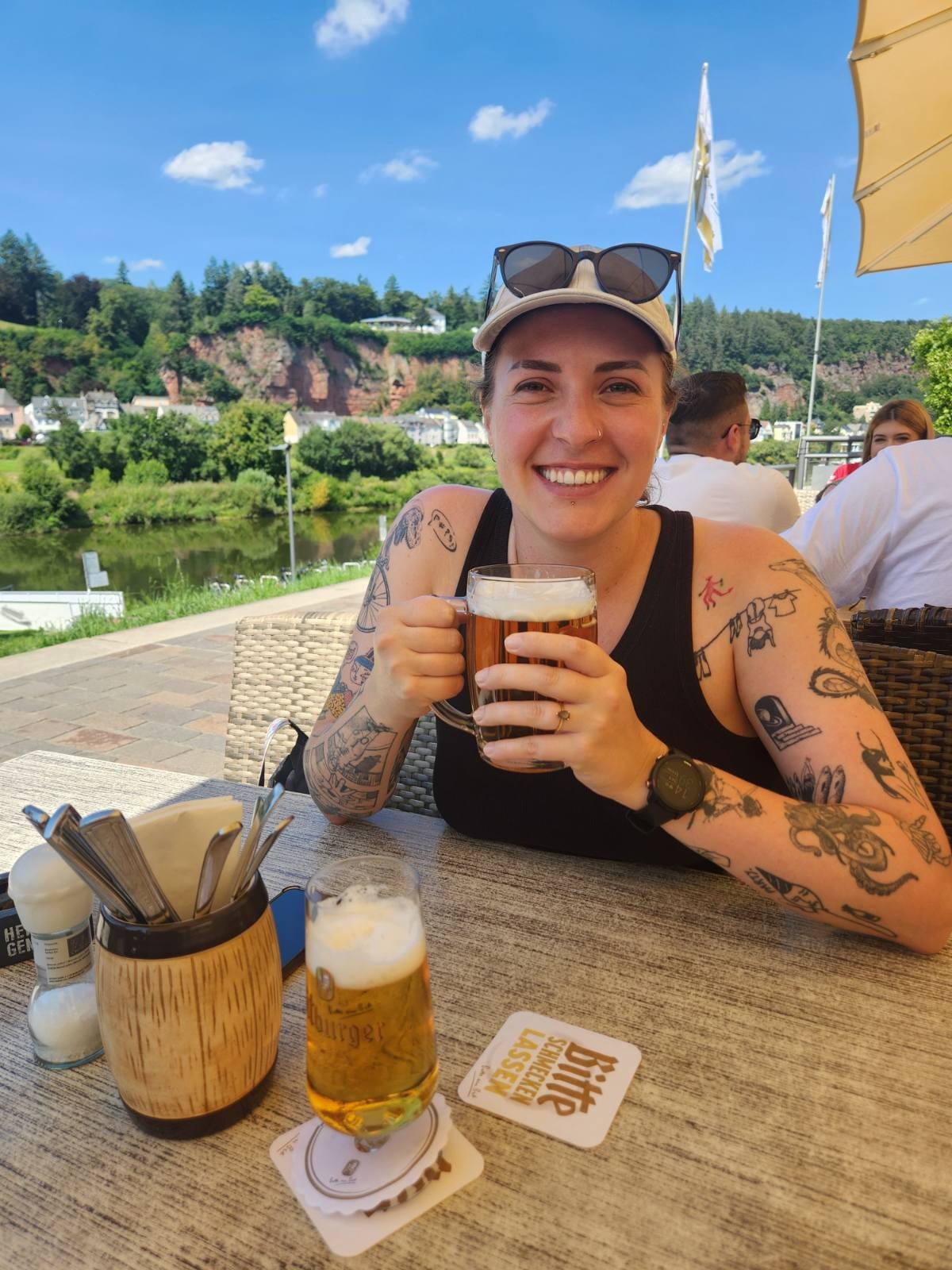 Lodeme smiles whild holding a beer on a restaraunt patio next to the Mosel river.