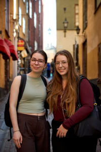 two young women wearing backpacks stand in a Stockholm street
