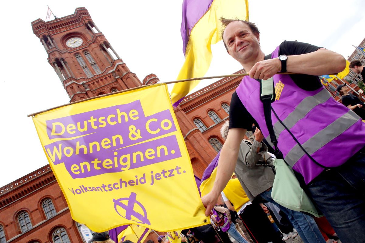 A Deutsche Wohnen & Co activist waves a flag in front of Berlin's Rote Rathaus