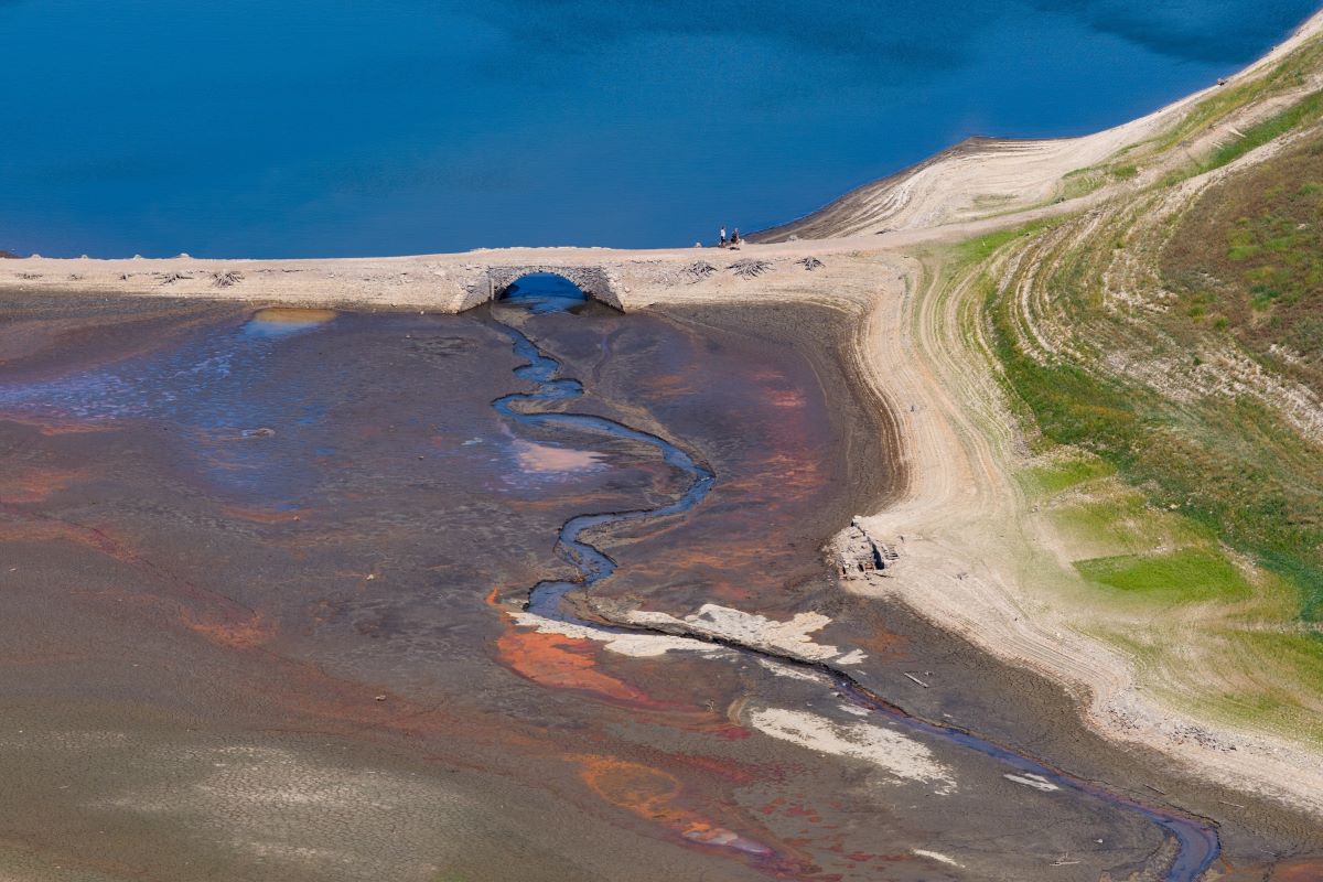 a crumbling bridge with water on one side and mud on the other