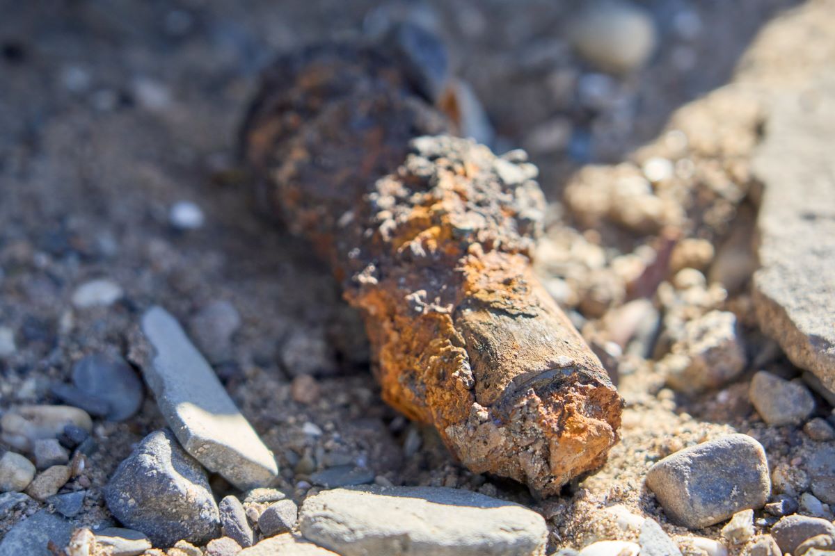 an old rifle grenade lies on a dry river bed