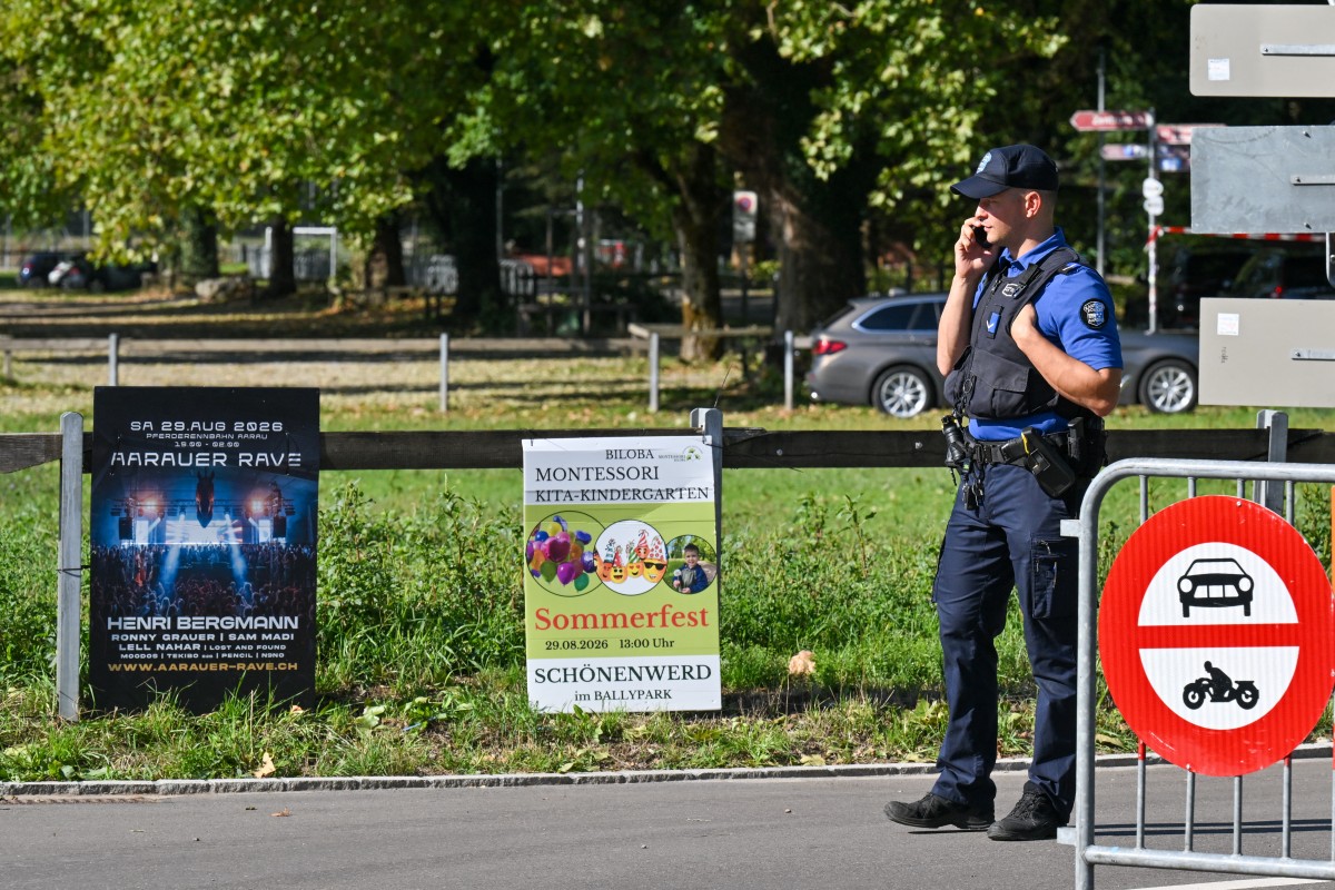 Police officers secure the area next to a poster advertising a rave where a shooting occurred, in Aarau, northern Switzerland