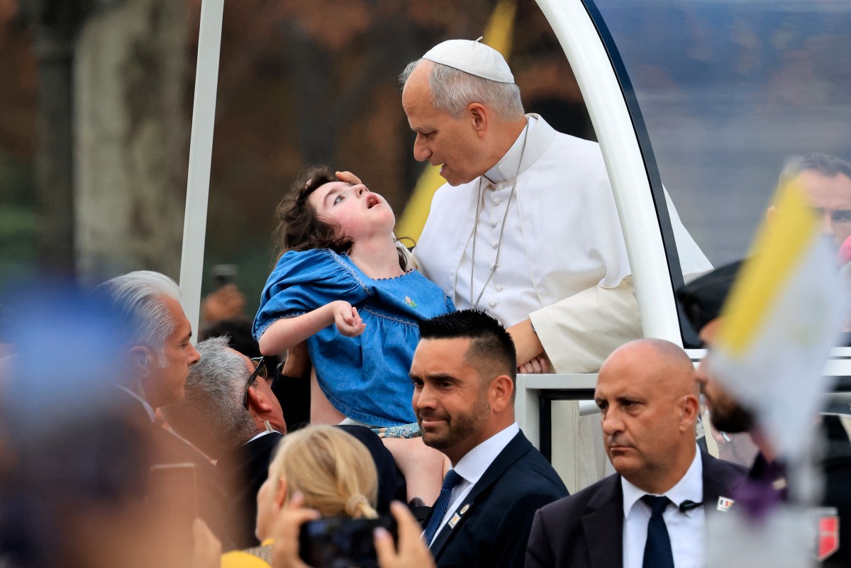 Pope Leo XIV blesses a child as he rides down the Champs-Elysees Avenue in the Papamobile (popemobile) on his way to the Place de la Concorde, central Paris